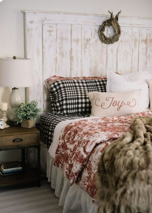Faux fur blankets, plaid bedding, a wooden wreath and potted greenery make the bedroom winter like and cozy