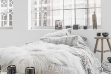 faux fur, candles, bowls and a rough wooden bench plus a knit pillow are ideal for a winter-like Scandinavian bedroom