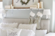 faux fur stockings and pillows, a Christmas sign and some pillar candles make the white bedroom super cozy and chic