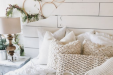 lots of hoop wreaths with greenery, knit and crochet pillows and blankets give the bedroom a cool and cozy winter look