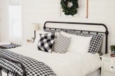 plaid bedding and a fresh greenery wreath over the bed make the bedroom clasically Christmassy