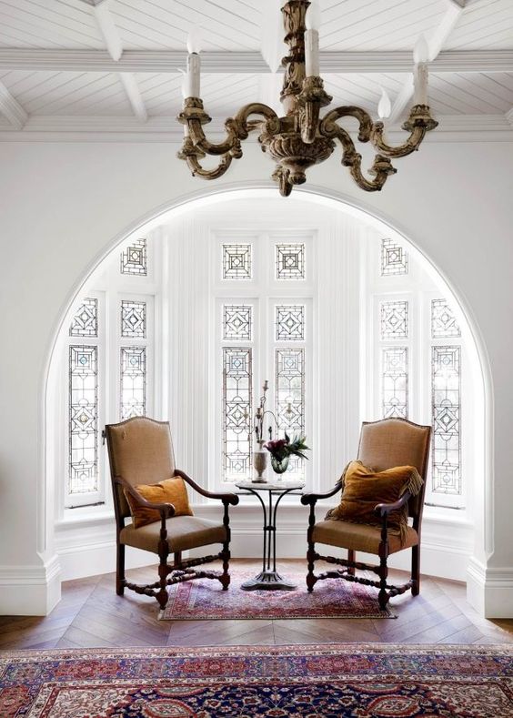 A beautiful alcove with a bay window with stained glass, a vintage table and carved chairs   this glass keeps privacy yet provides light