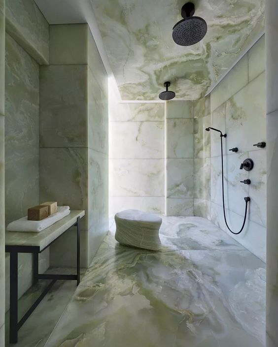 a breathtaking bathroom completely clad with green onyx and with black fixtures looks like a real sanctuary