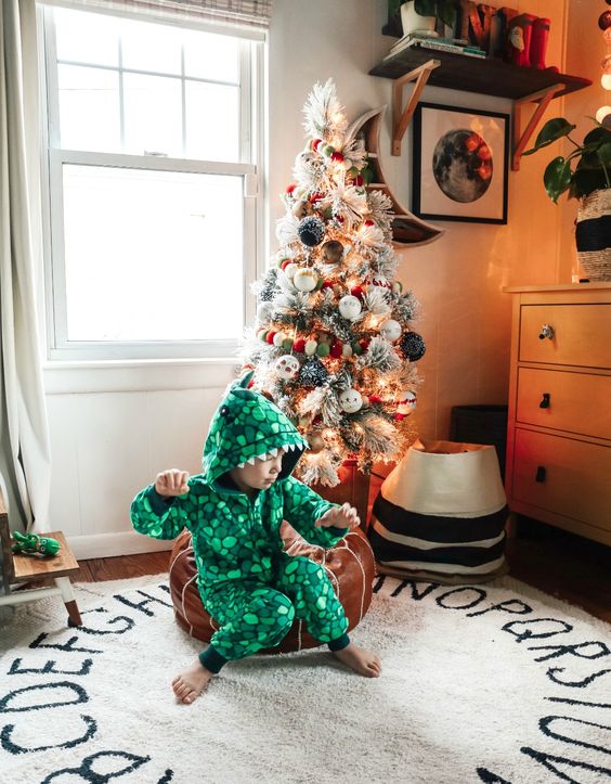 a flocked Christmas tree decorated with lights and pompom ornaments is a beautiful decoration you can provide for your kids