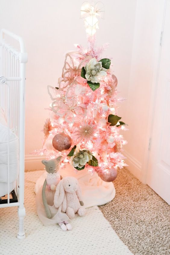 a lovely pink Christmas tree with lights, fabric blooms and pink ornaments is amazing for a little princess nursery at Christmas