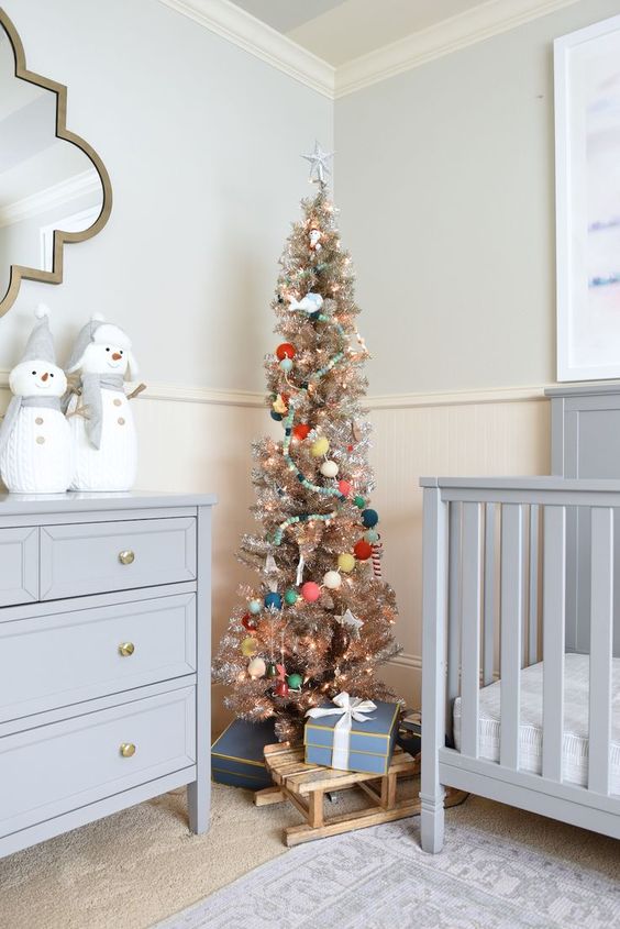 a metallic Christmas tree with lights, pretty ornaments and colorful pompom garlands is a lovely idea for any kids' room