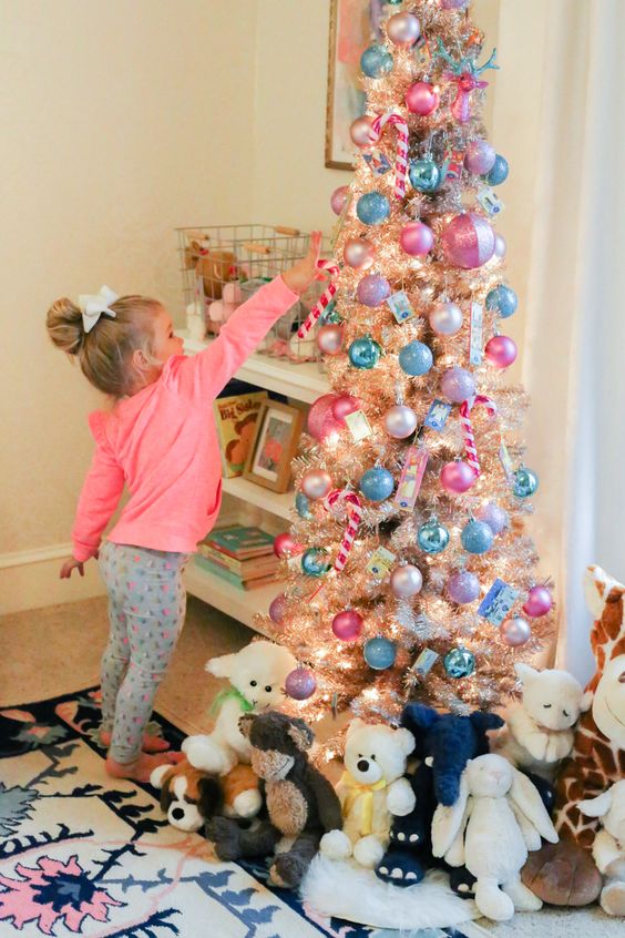 a shiny metallic Christmas tree with pink and blue ornaments, lights and toys under the tree is a lovely and bold idea