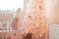 a white Christmas tree decorated with pastel ornaments, pink bows, a pink stocking and ornaments on the table for a little girl’s room