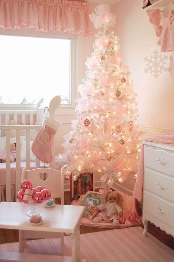a white Christmas tree decorated with pastel ornaments, pink bows, a pink stocking and ornaments on the table for a little girl's room