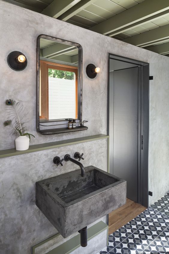 a catchy bathroom with a patterned tile floor, concrete walls and a floating sink, a mirror and bulbs plus a shelf