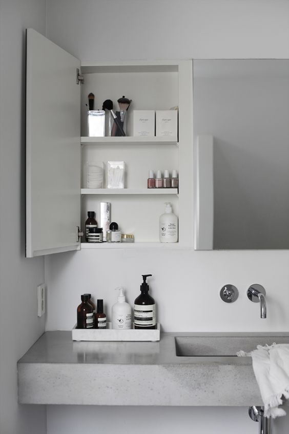 A contemporary bathroom with a mirror, built in cabinets and a concrete floating vanity plus simple fixtures looks fresh