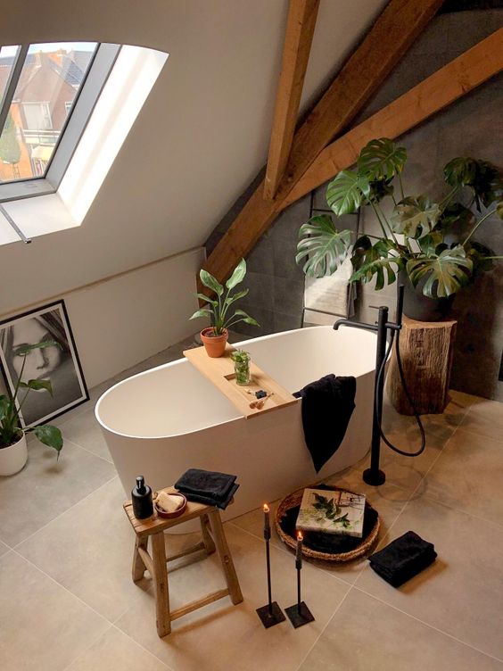 a contemporary bathroom with wooden beams, a grey tile wall, a bathtub, black textiles and candles