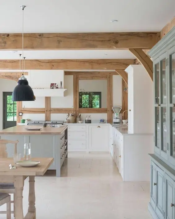 a contemporary kitchen with white cabinetry, a grey kitchen island and wooden detailing plus wooden beams is very cozy