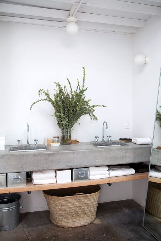 a contemporary rustic bathroom with a concrete floating vanity and a concrete floor, a wooden shelf, greenery and a floor mirror