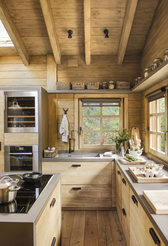 a contemporary wooden chalet kitchen with concrete countertops, skylights, wooden beams on the ceiling is chic and light-filled