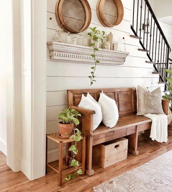 a cozy modern farmhouse entryway with a wooden bench, a stool, some wooden bowls and a whitewashed rack with bottles