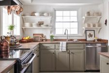 a cozy modern farmhouse kitchen with green cabinetry, wooden countertops and wooden beams that match and warm up the space