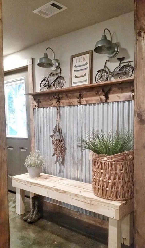 a farmhouse entryway with a corrugated steel wall, a rack with hooks, some metal lamps and a basket with greenery