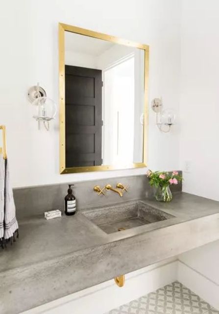 a floating concrete vanity with a sink, bold gold fixtures to glam up this nook for a cool and contemporary space