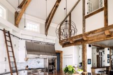 a modern farmhouse kitchen with white cabinetry, a grey kitchen island, wooden beams and countertops and pendant lamps