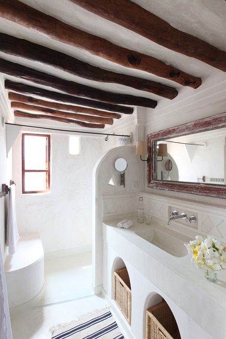a neutral bathroom in white, with rich stained beams, a shower space and a concrete vanity with storage space