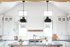 a neutral contemporary kitchen with dark stone countertops, wooden beams, a wooden kitchen islnd is welcoming and stylish