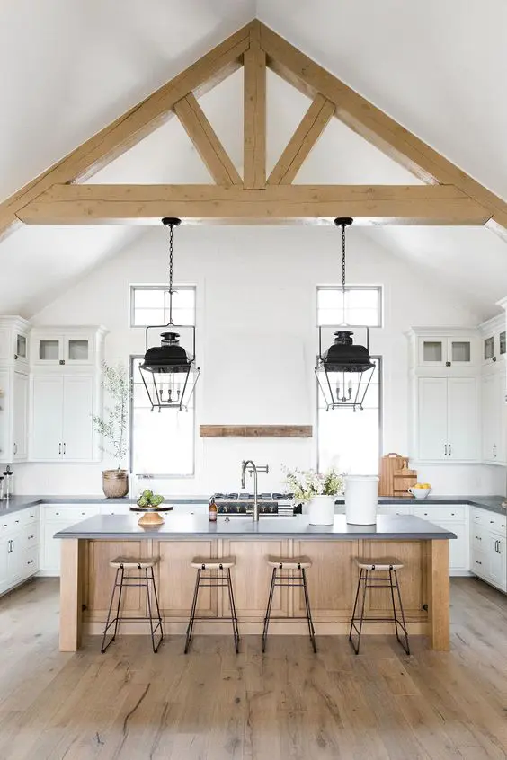 a neutral contemporary kitchen with dark stone countertops, wooden beams, a wooden kitchen islnd is welcoming and stylish