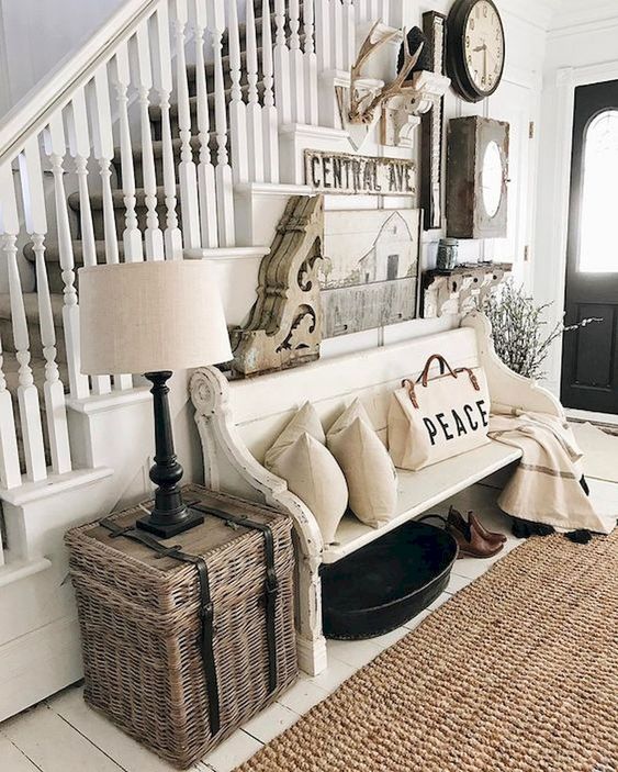 a neutral farmhouse entryway with a large and creative gallery wall, a white bench, neutral pillows and blankets plus a woven box