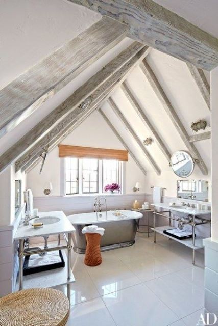 a neutral modern farmhouse bathroom with whitewashed wooden beams, a metal tub, two vanities and sinks