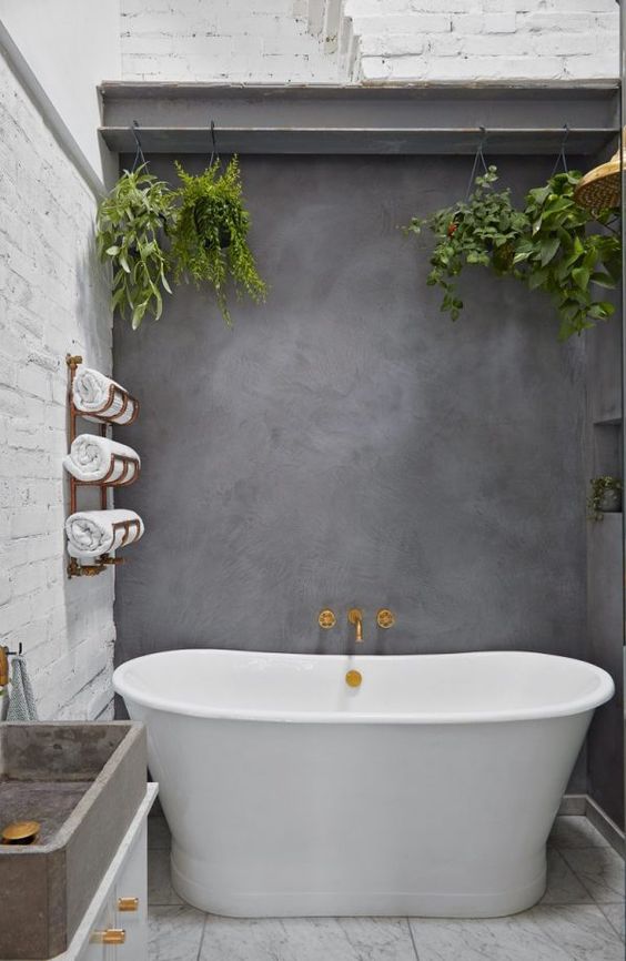 a stylish bathroom with white brick walls and a white stone floor, an oval tub and a concrete wall and sink