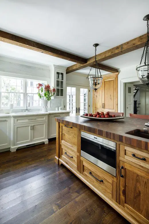 a vintage kitchen with neutral cabinets, a stained wooden kitchen island and wooden beams that match and look cozy