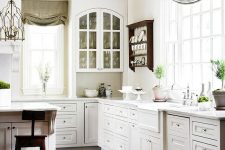 a vintage white kitchen with elegant cabinetry, dark wooden beams and sotols that add interest, grey and green curtains