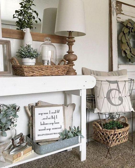 a white farmhouse console with baskets, wire baskets, a table lamp and much greenery for a vintage feel