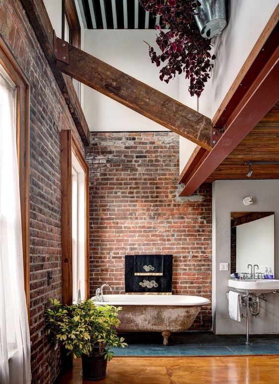 an industrial bathroom with brick walls, a shabby chic tub, wooden beams and a vintage sink