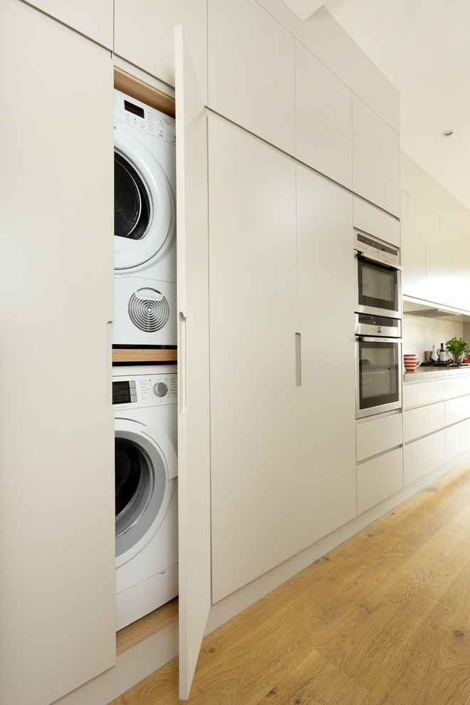 Custom cabinets allow to hide both a washing machine and a dryer without losing any space. (Cue &amp; Co of London)