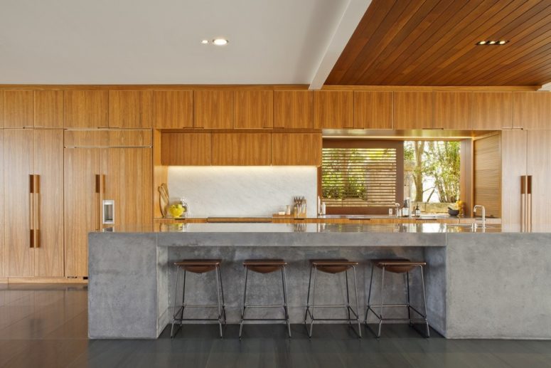 a rich-stained wooden kitchen with a concrete kitchen island and leather stools  (Richard Cole Architecture)