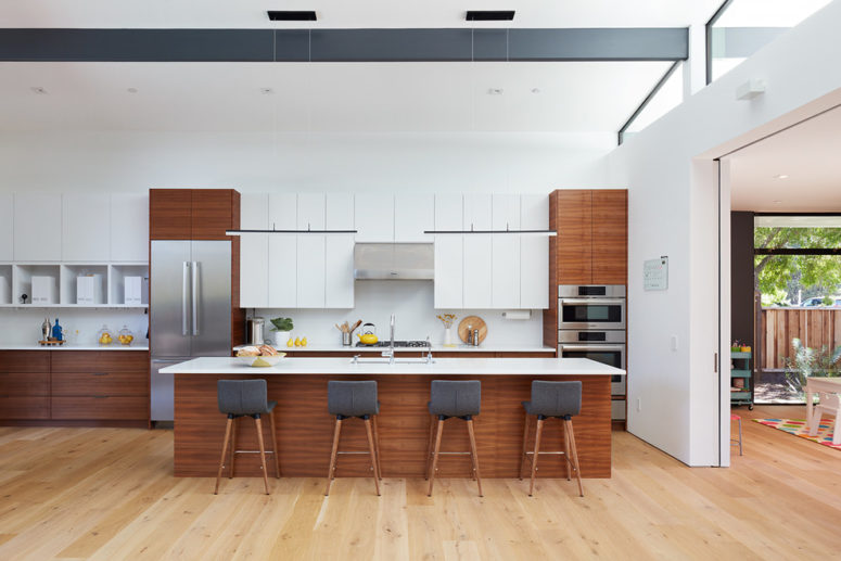 a rich-stained and white mid-century modern kitchen with black chairs and a large kitchen island  (Klopf Architecture)