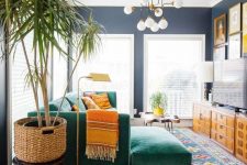 a bold mid-century modern living room with colorful printed rugs, an emerald sectional, printed pillows, stained storage unit and a colorful gallery wall