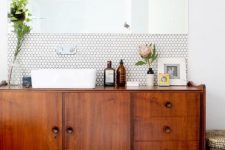 a chic mid-century modern space with white hex tiles and black usual ones, a rich stained vnaity and a statement mirror