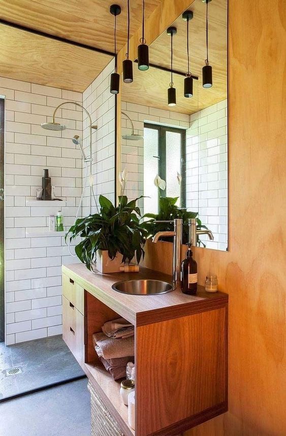 A chic mid century modern space with white subway tiles, lots of plywood and wood, black pendant lamps over the sink