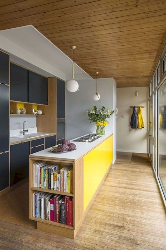 a colorful mid-century modern kitchen with navy cabinets, a yellow kitchen island and sphere lamps