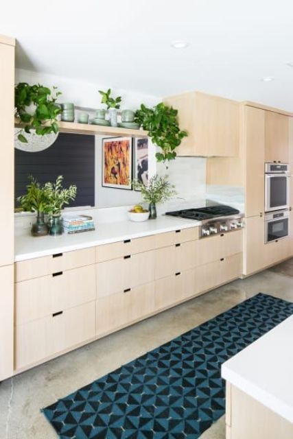 a light-colored mid-century modern kitchen of plywood, a mosaic rug and much greenery