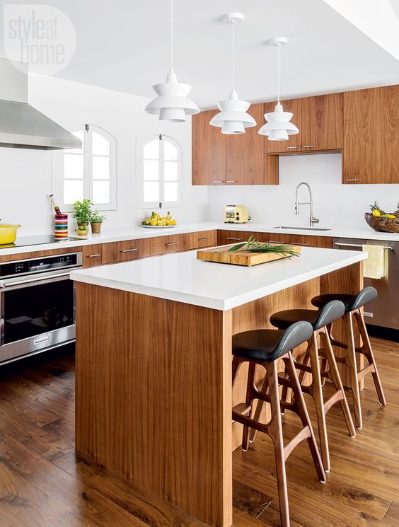 a light-filled mid-century modern kitchen with rich-stained cabinets, white countertops, white sculptural pendant lamps