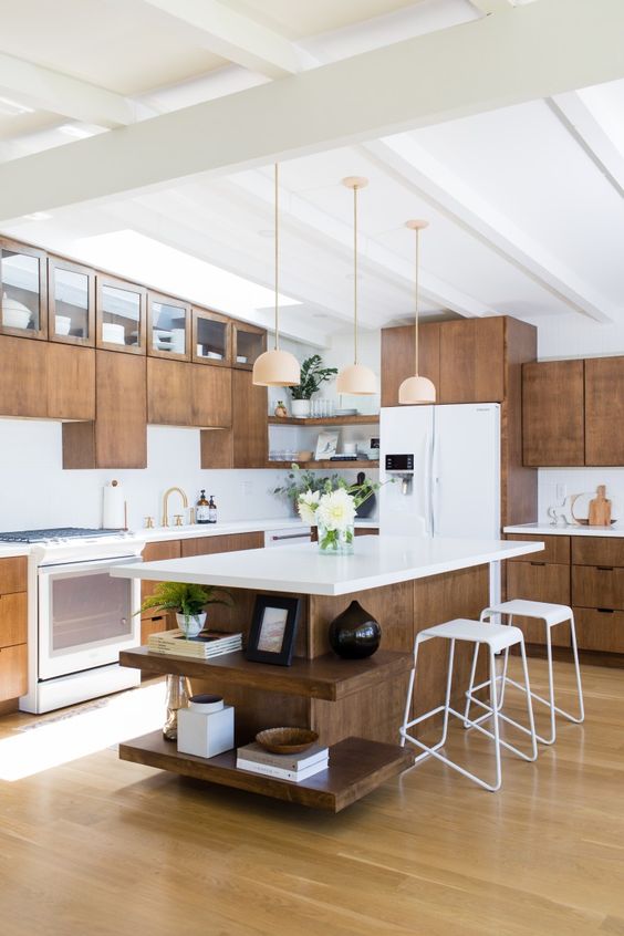 a mid-century modern kitchen with wooden cabinets, white countertops, pendant lamps and white stools