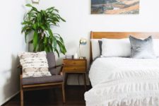 a mid-century modern meets boho bedroom with warm-colored wooden furniture, an artwork, pendant lamps and a potted plant