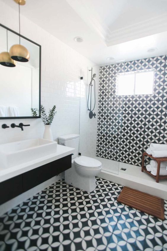 a monochromatic bathroom with black and white tiles, a black floating vanity and white appliances plus brass lamps