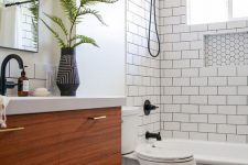 a monochromatic bathroom with white subway tiles and black hex ones, a wooden vanity and black fixtures for a bolder look