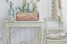 a neutral shabby chic entryway with pastel furniture – a chair, a console, a shelf, a box with blooms and a basket