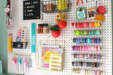 a pegboard done with various shelves, ledges, hooks and hangings plus plastic containers on the desk