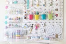 a pegboard spruced up with colorful cups, containers, hooks, acrylic ledges and other stuff